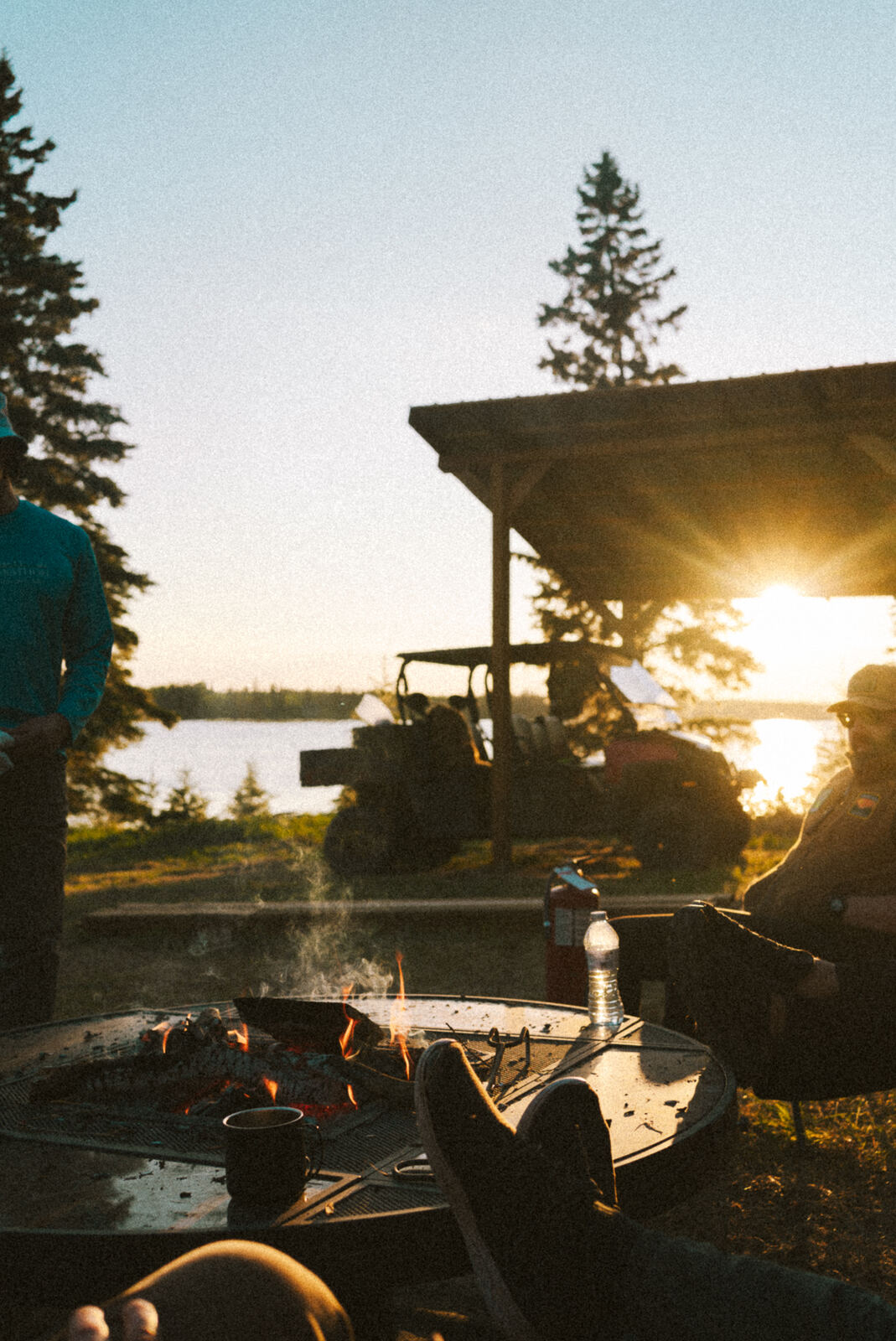 Silhouettes around the grill at the gazebo as the sun drops