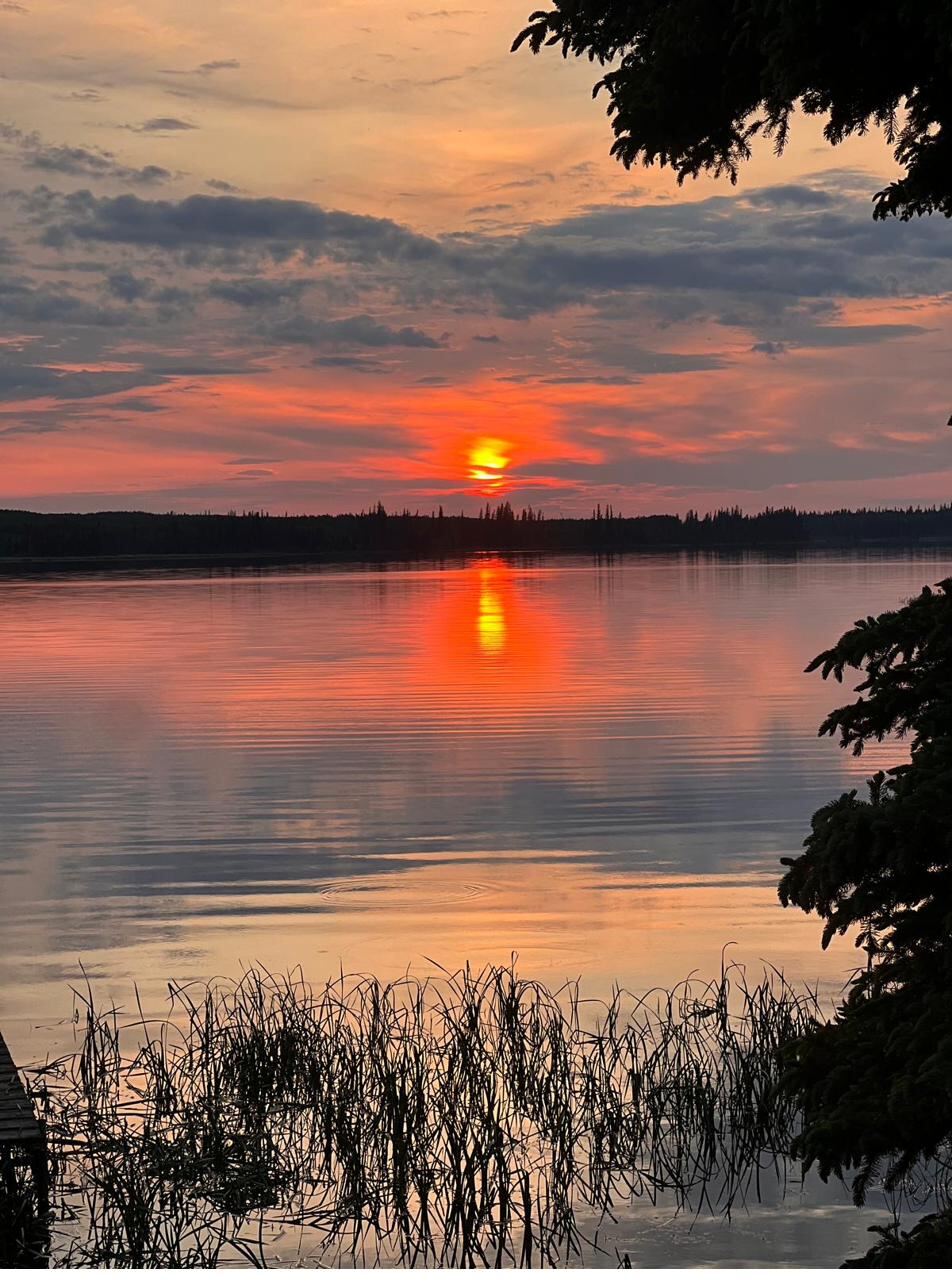 The sun low and red over the lake, mirrored in still water