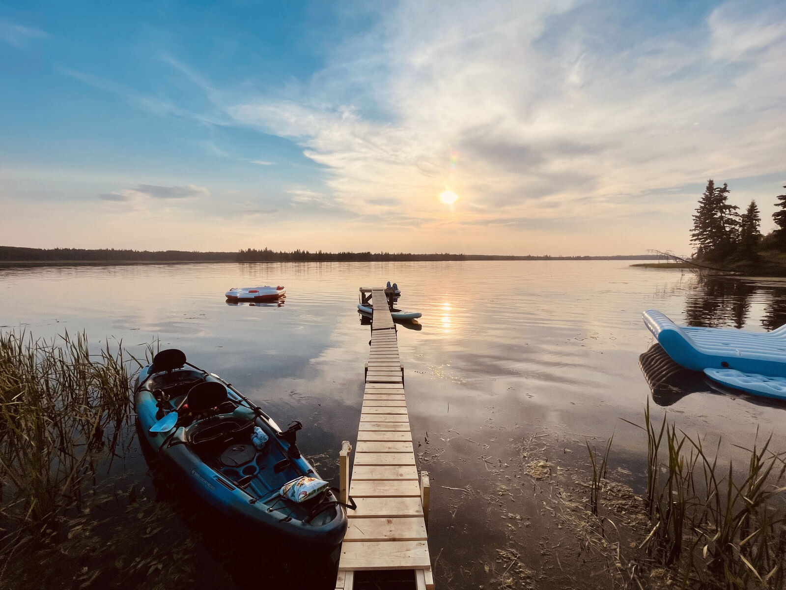 Kayaks resting beside the dock at dusk, lake gone still