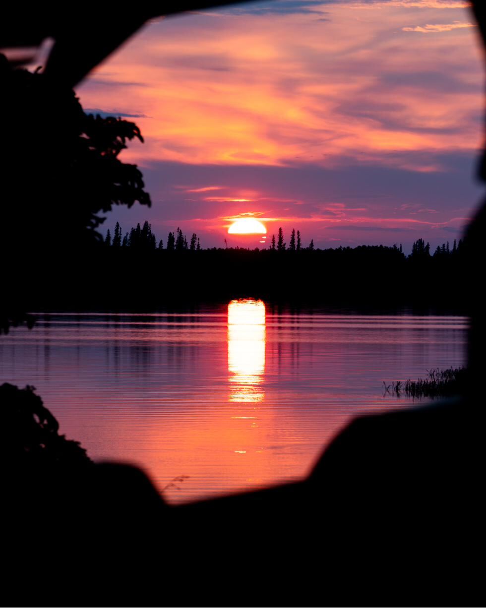 The lake gone perfectly still at dusk, sky mirrored in the water
