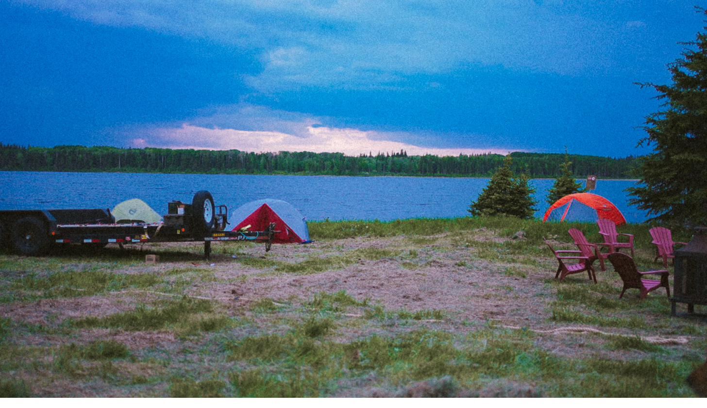 Tents along the lakeshore at dusk under a wide northern sky