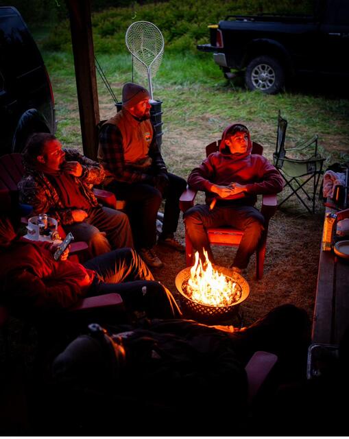 Faces lit by firelight around the ring