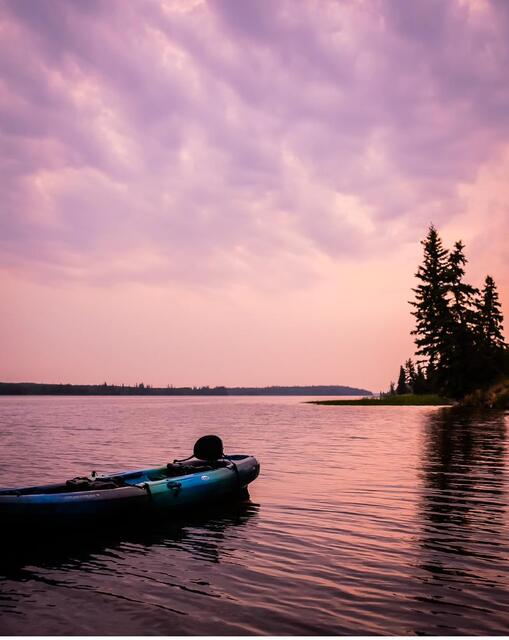 A kayak resting on pink water at dusk