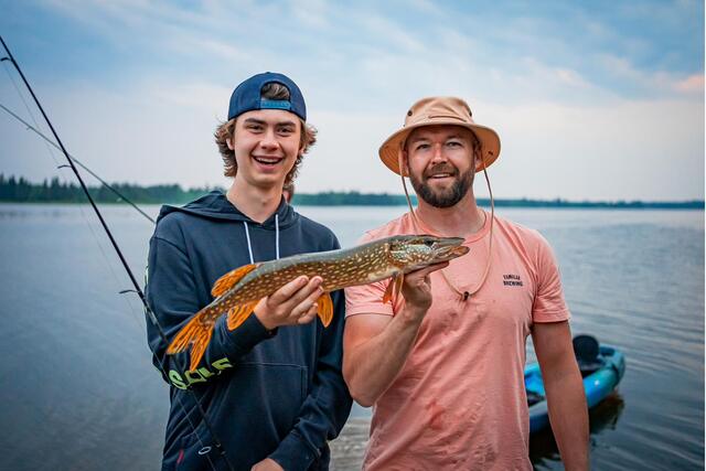 The younger generation holding a northern pike with a grin