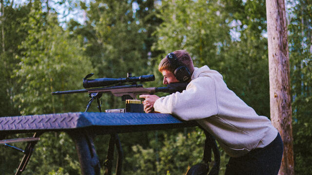Prone behind the rifle, settled in for the long shot